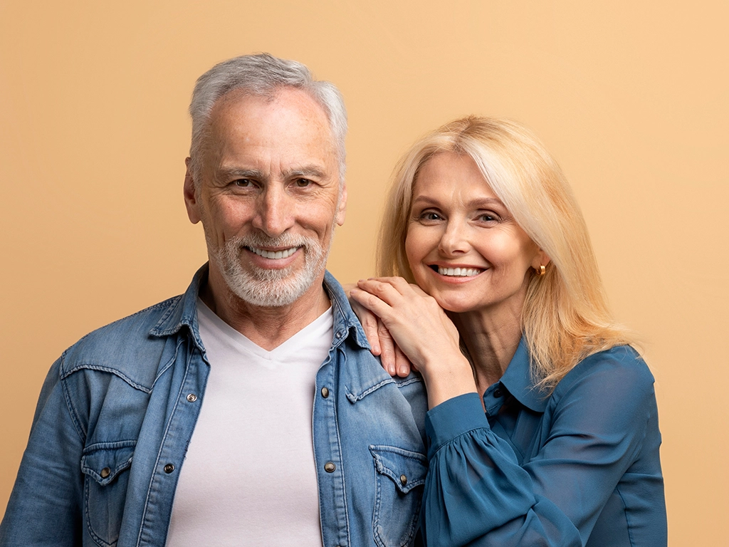 Happily married mature couple posing on beige background